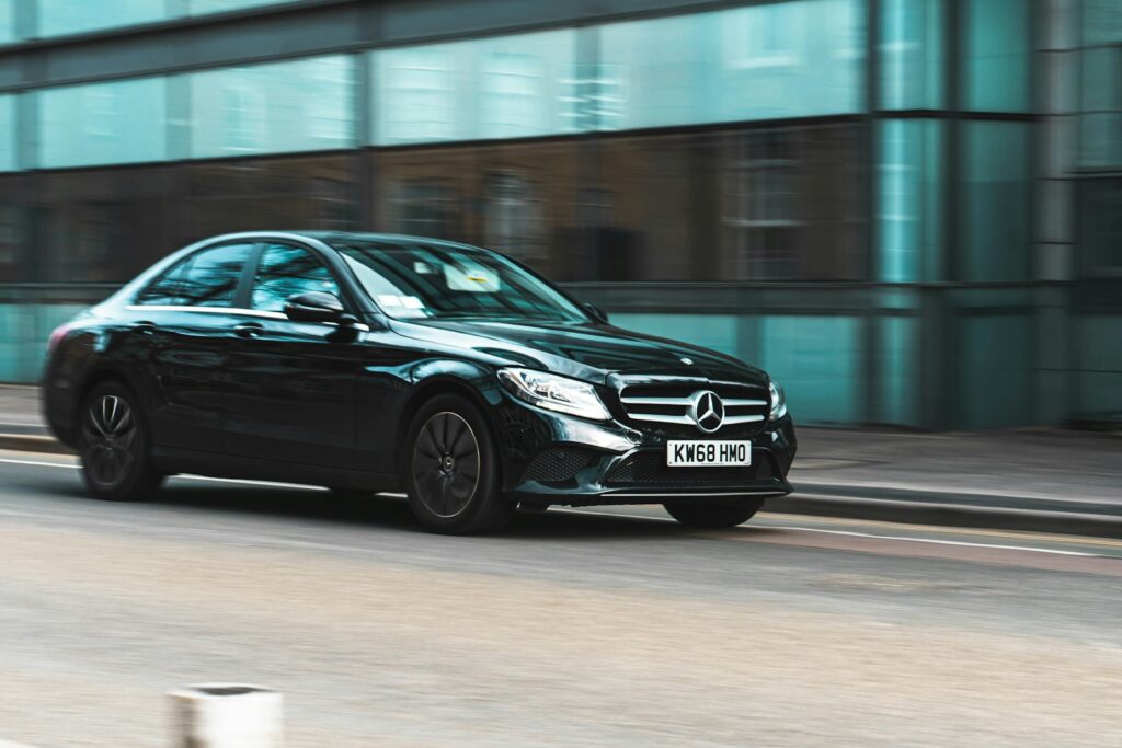 Black Mercedes saloon driving through a city street
